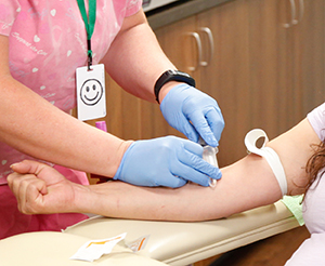 Proveedor de atención médica que extrae sangre del brazo de una mujer.